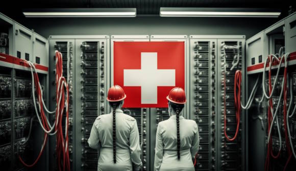 Zwei Personen in einem Serverraum. An der Wand eine Schweizer Flagge 