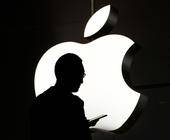 Silhouette einer Person mit Smartphone vor einem weissen Apple-Logo