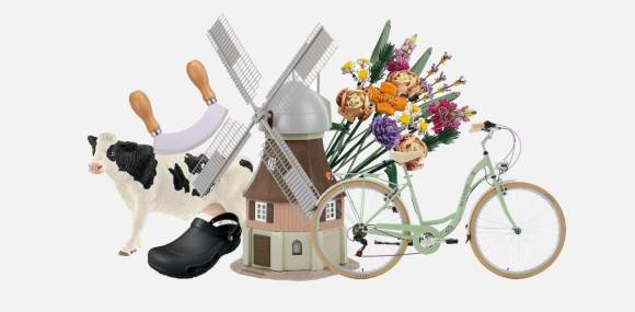 Stillleben aus Windmühle, Kuh, Fahrrad, Gummi-Clogs und Schnittblumen 