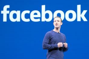 Mark Zuckerberg steht vor einer Wand mit Facebook-Logo 