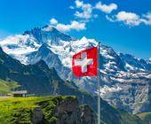 Symbolbild zeigt eine Alpenlandschaft mit wehender Schweizer Fahne
