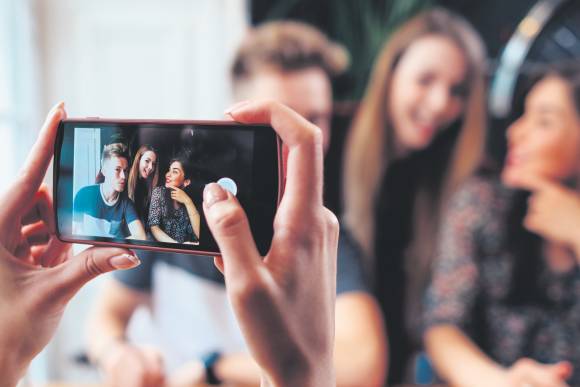 Der Porträt-Modus gehört zu den wichtigsten Funktionen der iPhone-Kamera Eine Gruppe junger Leute wird mit einem iPhone fotografiert