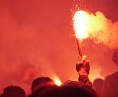 Symbolbild zeigt Rauchschwaden und Personen, die Pyros zünden