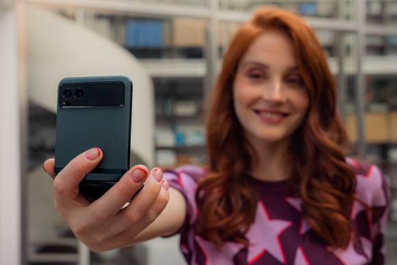 Eine Frau hält das halb zugeklappte Motorola Razr 40 für ein Selfie vor sich 