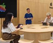 Symbolbild zeigt vier Personen, die mit ihren Tablets an einem Tisch in einem Apple-Shop sitzen oder stehen